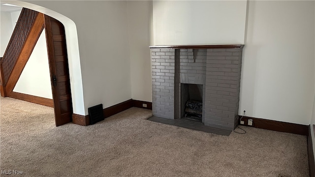 unfurnished living room with carpet and a brick fireplace