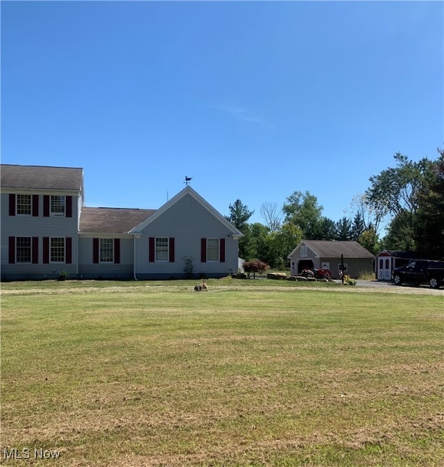 view of front of home featuring a storage unit and a front yard