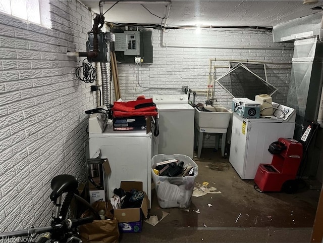 clothes washing area featuring brick wall, independent washer and dryer, and electric panel