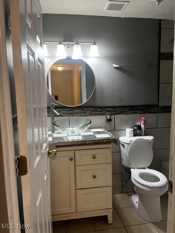 bathroom with vanity, toilet, a textured ceiling, and tile patterned flooring