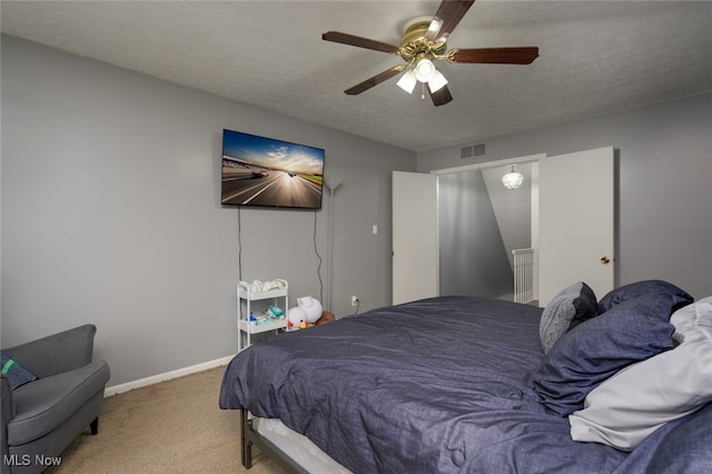 carpeted bedroom with ceiling fan and a textured ceiling