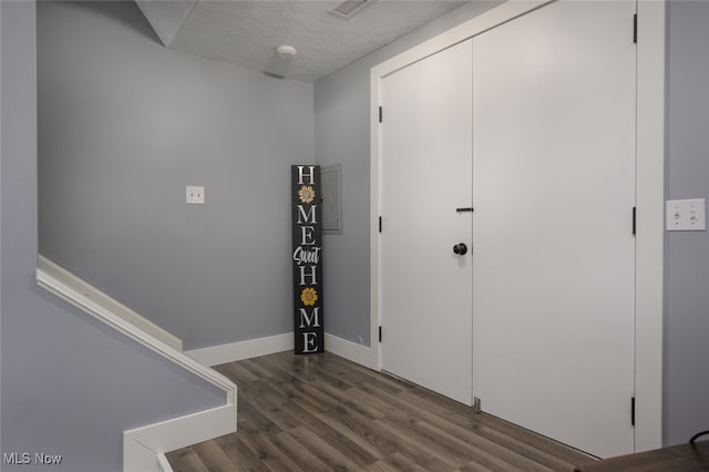 foyer entrance featuring a textured ceiling and dark wood-type flooring