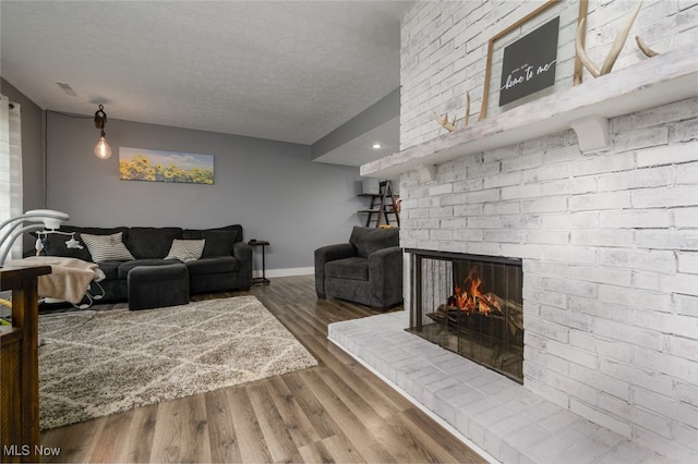 living room with a fireplace, a textured ceiling, and hardwood / wood-style flooring