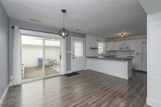 kitchen featuring white appliances, white cabinets, dark hardwood / wood-style floors, decorative light fixtures, and kitchen peninsula