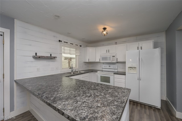 kitchen with kitchen peninsula, dark hardwood / wood-style flooring, white appliances, sink, and white cabinets