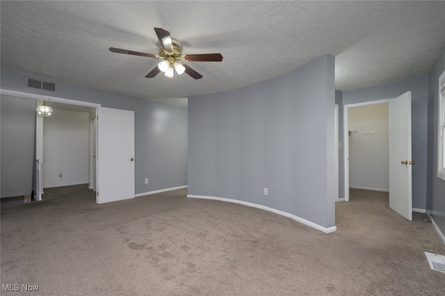 carpeted spare room featuring a textured ceiling and ceiling fan