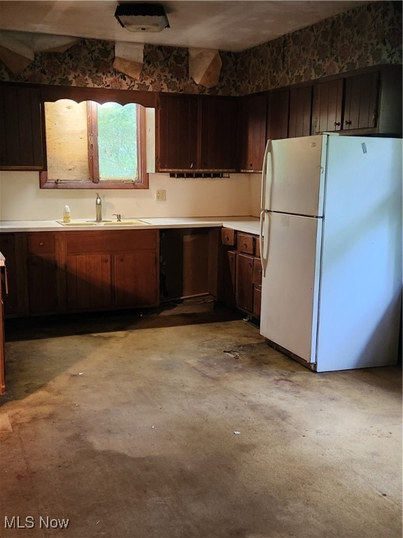 kitchen featuring white fridge, dark brown cabinetry, and sink