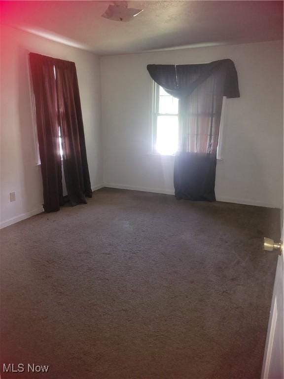 carpeted empty room featuring baseboards