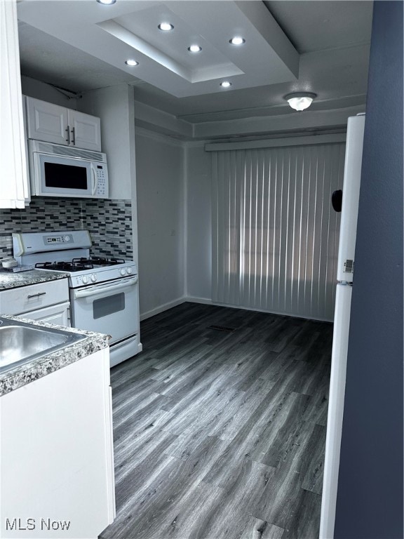 kitchen featuring white cabinetry, dark wood-type flooring, white appliances, and tasteful backsplash