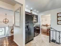 kitchen with black refrigerator with ice dispenser and light hardwood / wood-style floors