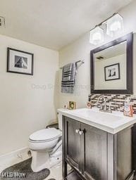 bathroom featuring vanity, toilet, and decorative backsplash