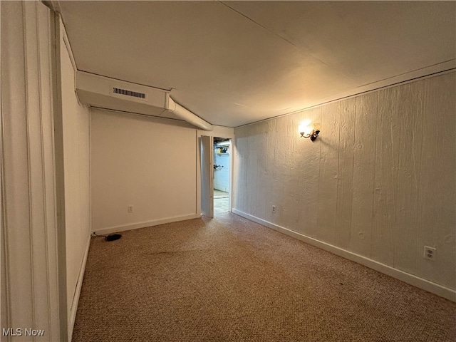 carpeted empty room with wood walls