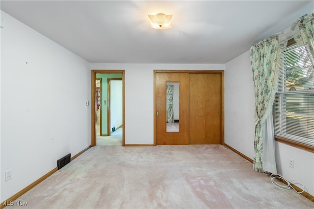 unfurnished bedroom with light colored carpet and a closet