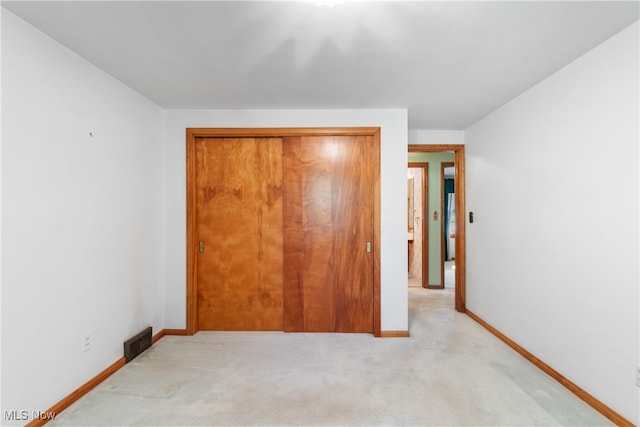 unfurnished bedroom with light carpet and a closet