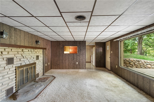 unfurnished living room featuring a brick fireplace and wooden walls