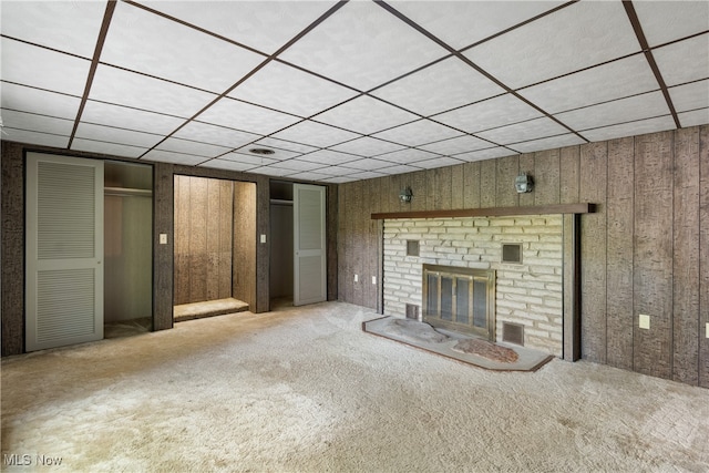 unfurnished living room with wood walls, a fireplace, and a drop ceiling