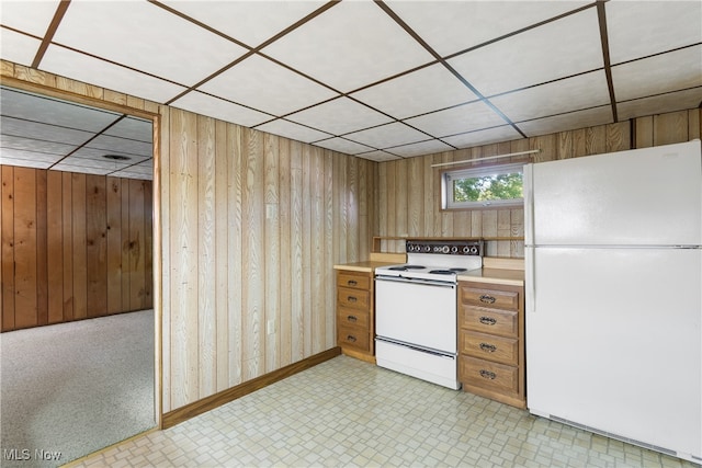 kitchen featuring white appliances, wooden walls, and a drop ceiling