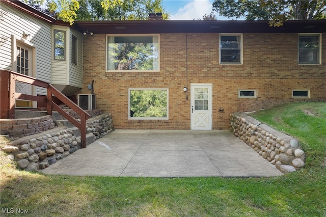 rear view of property with a lawn, a patio, and central AC