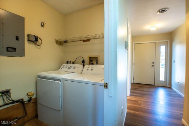 laundry room with electric panel, washer and clothes dryer, and hardwood / wood-style floors