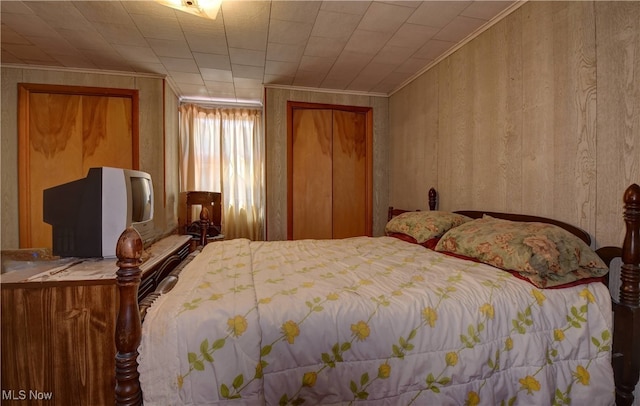 bedroom featuring crown molding and wood walls