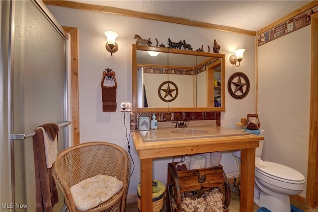 bathroom with toilet, sink, and a shower with door