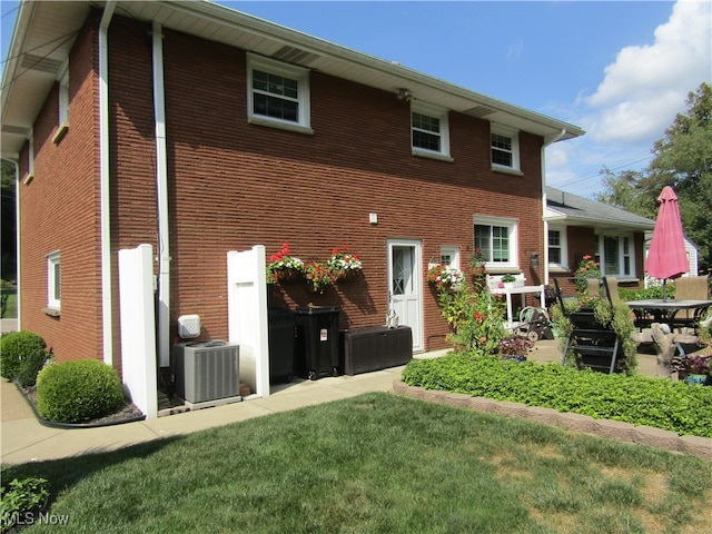 rear view of property with a yard and central AC unit