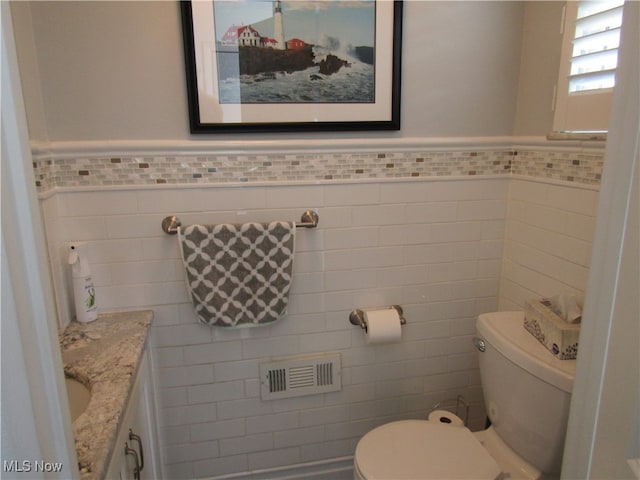 bathroom featuring tile walls, toilet, and vanity