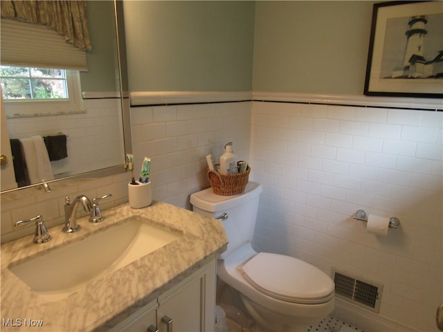 bathroom featuring vanity, toilet, and tile walls