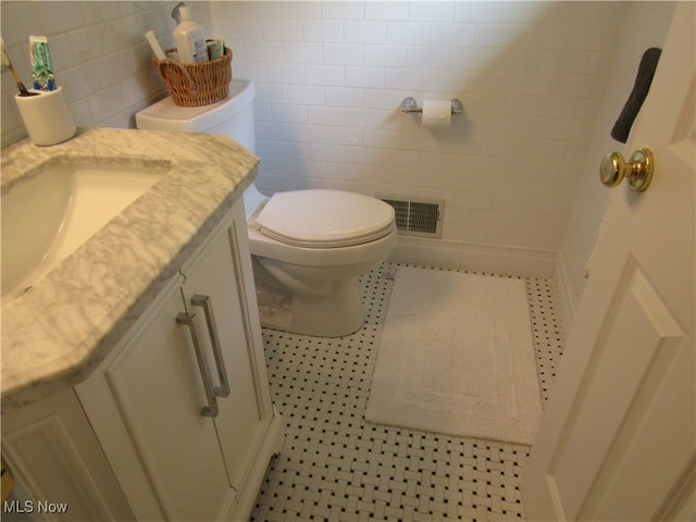 bathroom with vanity, toilet, tile walls, and tile patterned floors