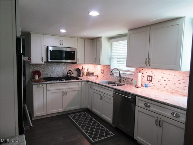 kitchen with dark hardwood / wood-style floors, light stone countertops, backsplash, appliances with stainless steel finishes, and sink