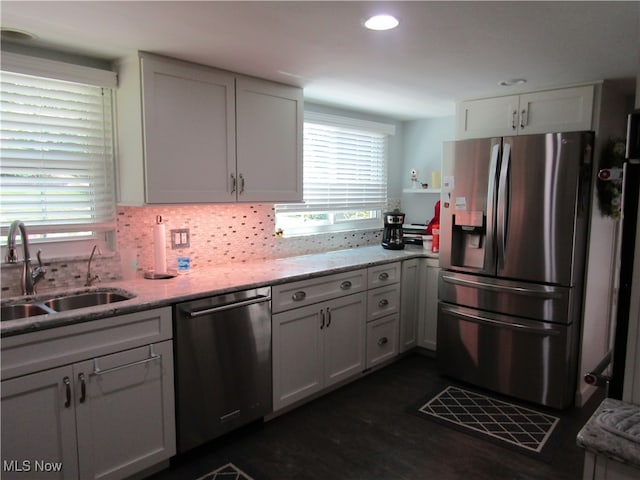 kitchen featuring white cabinets, appliances with stainless steel finishes, light stone counters, dark hardwood / wood-style flooring, and sink