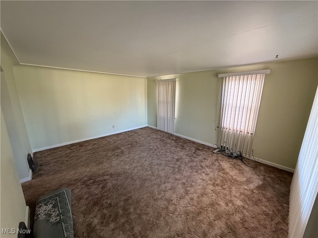 spare room featuring dark carpet