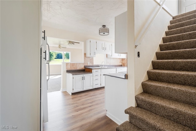 staircase with hardwood / wood-style flooring, sink, and ceiling fan