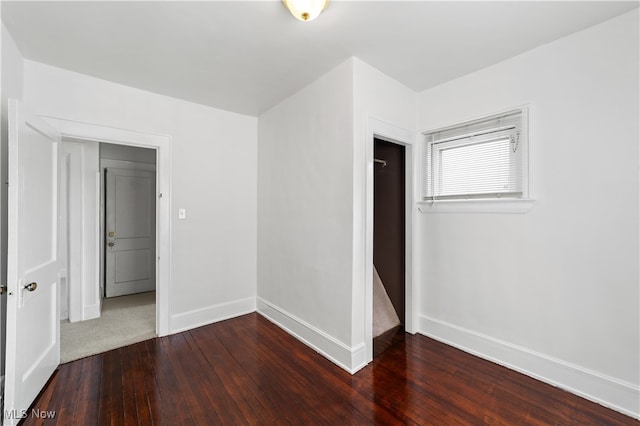 unfurnished bedroom with dark wood-type flooring and a closet