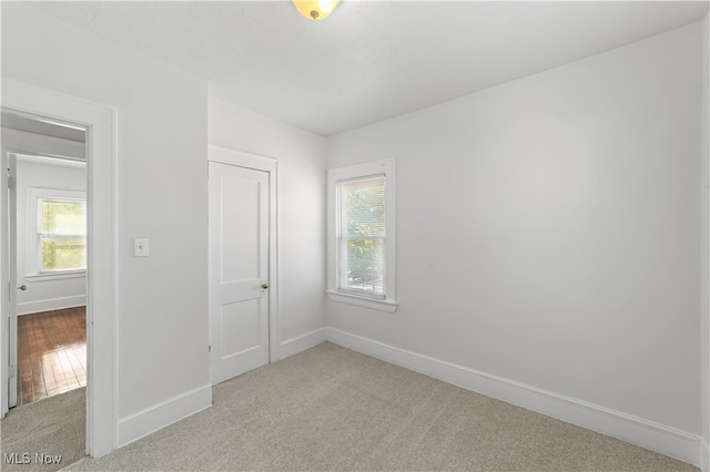 unfurnished bedroom with light colored carpet and a closet