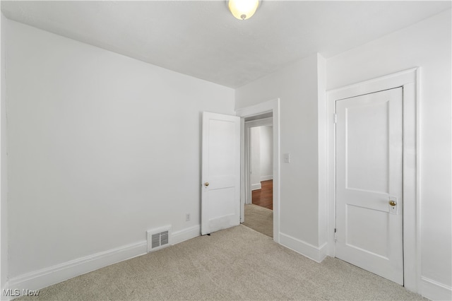 unfurnished bedroom with a closet and light carpet