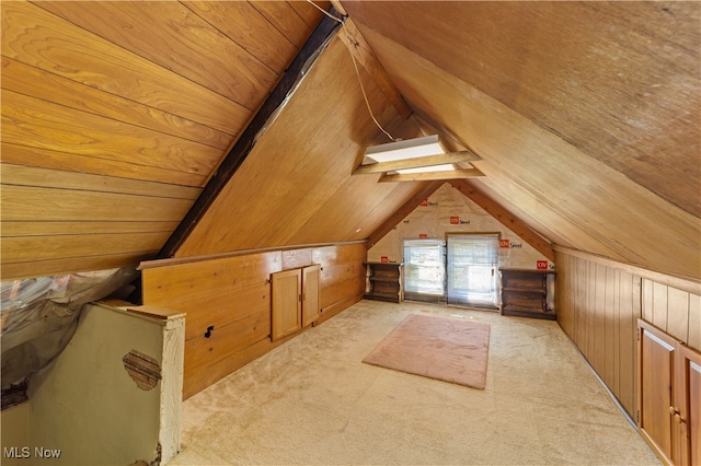 additional living space featuring lofted ceiling, light colored carpet, and wooden walls