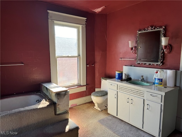 bathroom featuring vanity, toilet, and a washtub