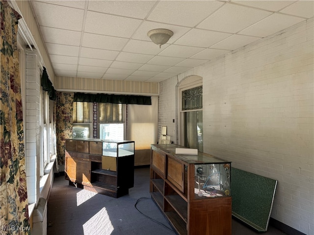 miscellaneous room with brick wall and a paneled ceiling