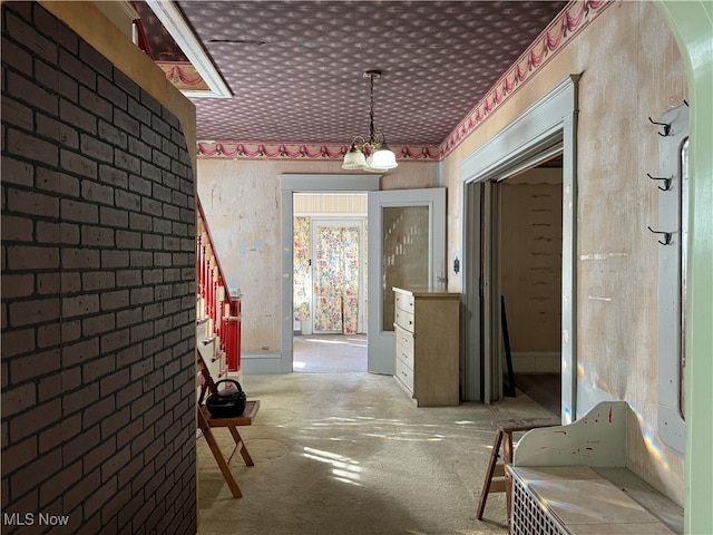 corridor with carpet flooring and a notable chandelier