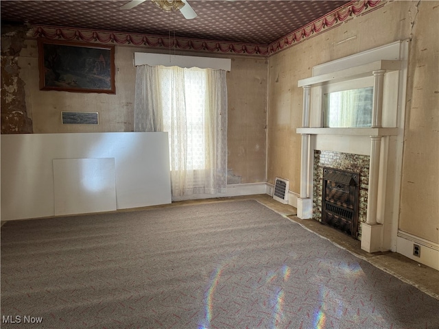 unfurnished living room with ceiling fan and a tiled fireplace