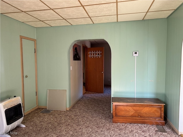 interior space with a drop ceiling, heating unit, and carpet flooring