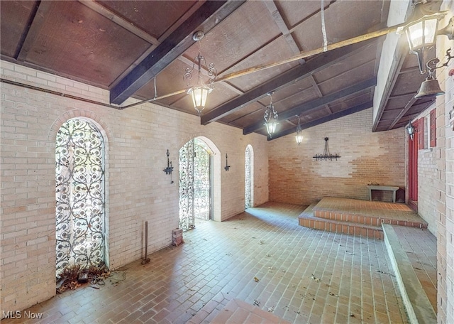 interior space with high vaulted ceiling, brick wall, and beam ceiling