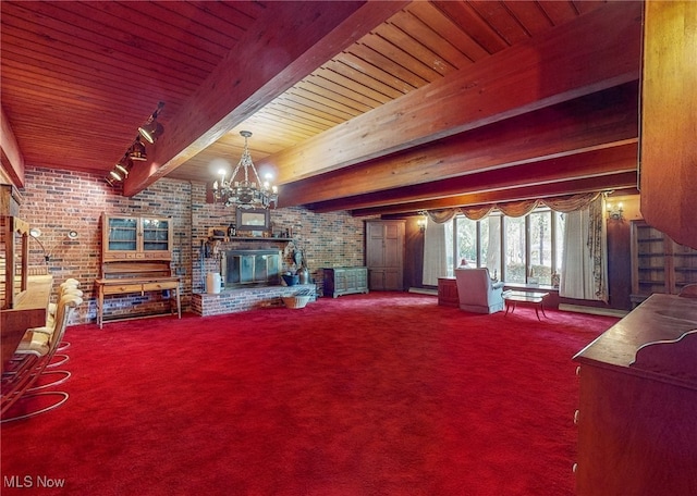 living room with a brick fireplace, a chandelier, beamed ceiling, brick wall, and carpet floors