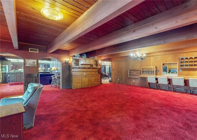 interior space with beam ceiling, a notable chandelier, and carpet floors