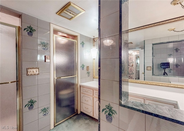 bathroom featuring tile walls, walk in shower, and vanity