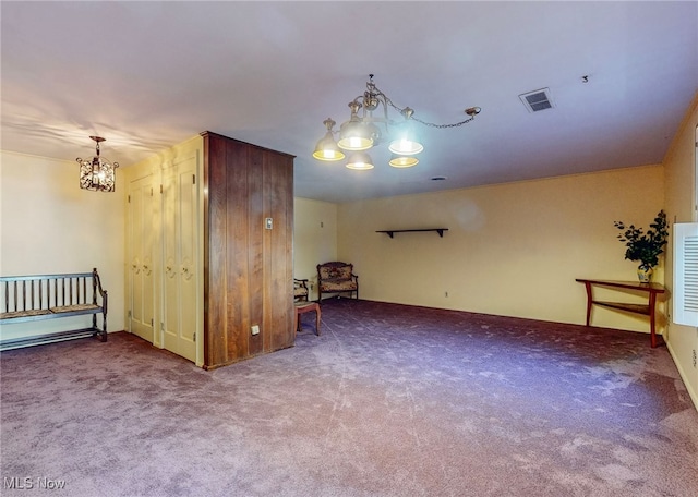 carpeted spare room featuring a chandelier