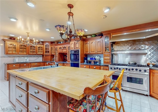 kitchen featuring an inviting chandelier, light tile patterned floors, tasteful backsplash, an island with sink, and stainless steel appliances