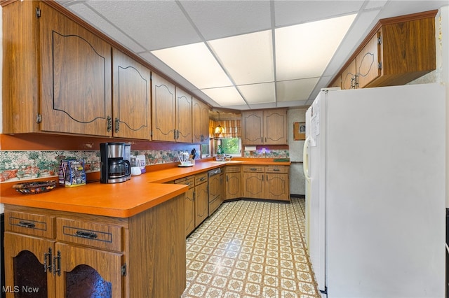 kitchen featuring white refrigerator, dishwasher, and a paneled ceiling