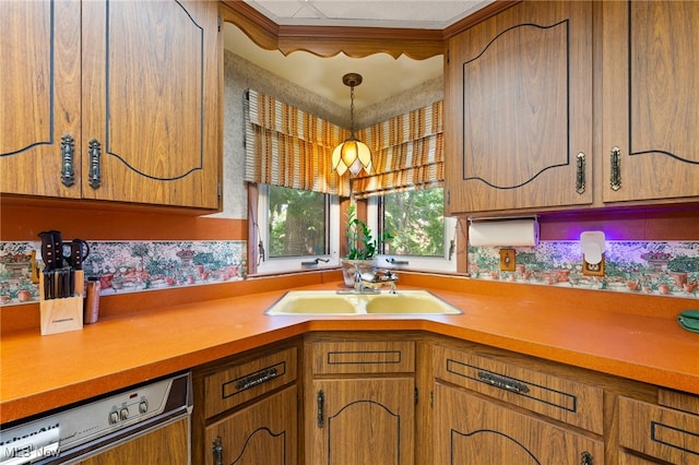 kitchen featuring decorative light fixtures, dishwashing machine, and sink